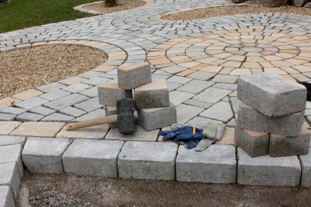 image of landscaping Ballarat's pavers stacked and ready to be laid with a mallet and gloves close by